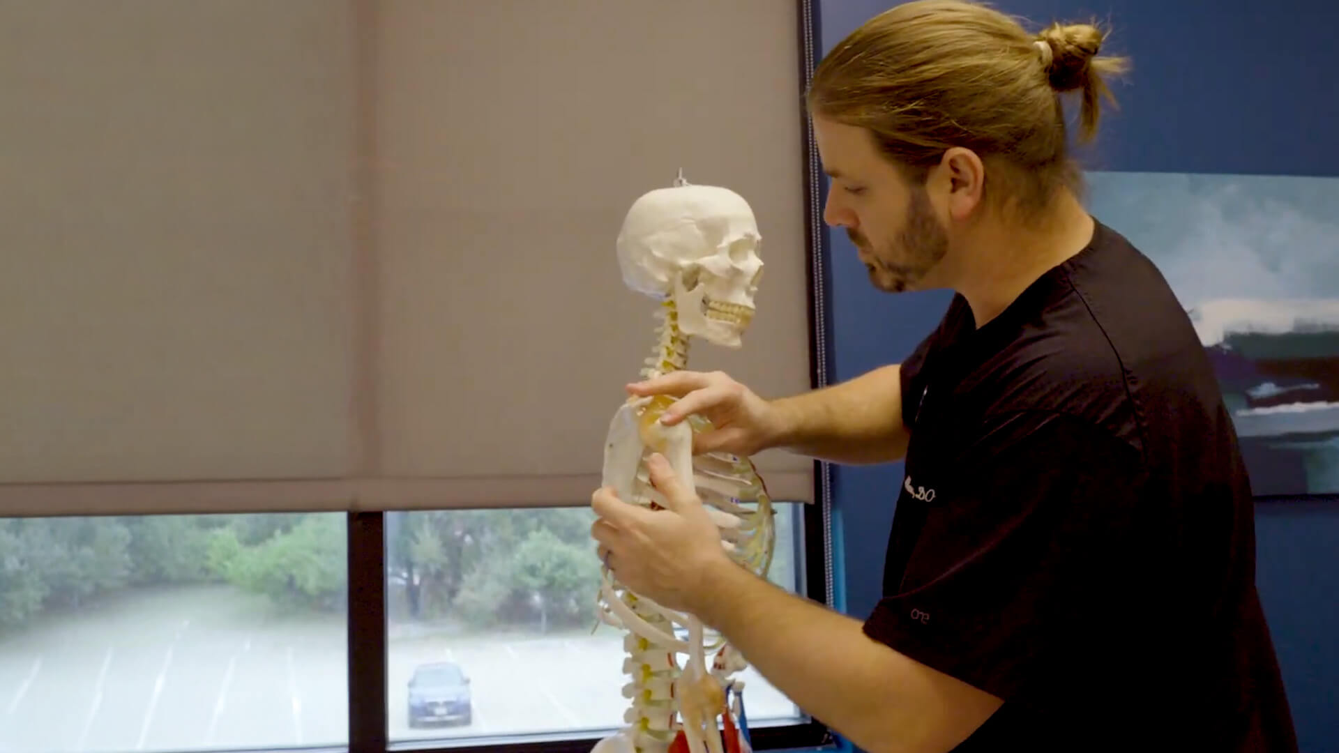 Healthcare professional examines a spine model at CHARM in Austin, TX, emphasizing musculoskeletal education and patient care.